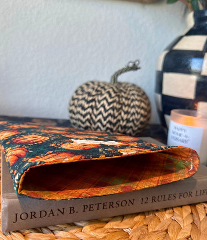 Open handmade quilted book sleeve showing orange lining with a book sliding in, styled with autumn props