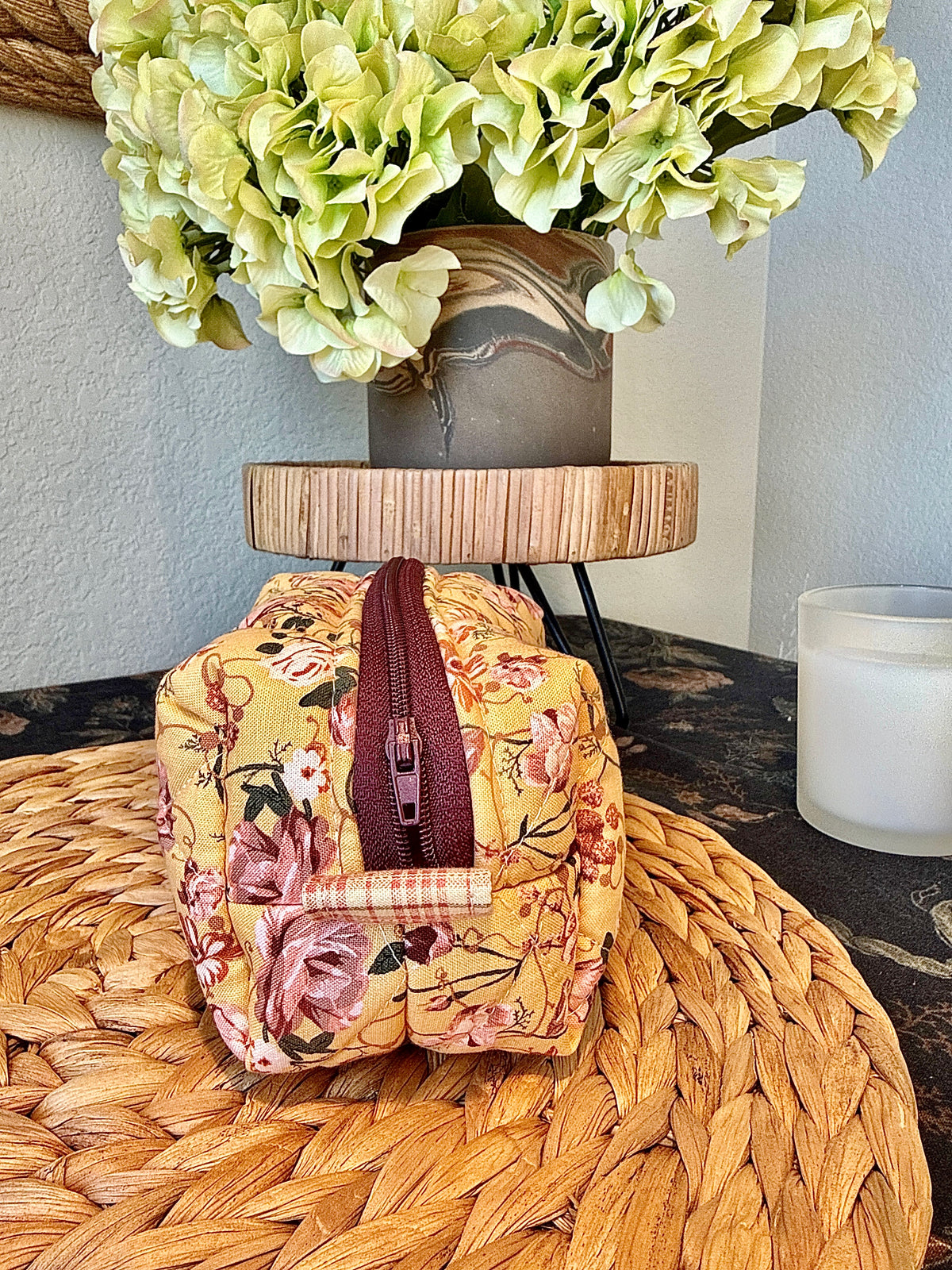 Side view of small golden floral quilted boxy bag showing its burgundy zipper and side pull tab