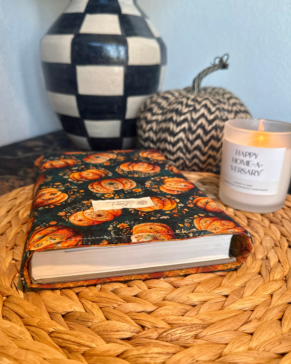 (sleeve wrapped with book inside, front view)
Front view of handmade quilted Gilded Gourd book sleeve wrapped around a hardcover book on a wicker charger