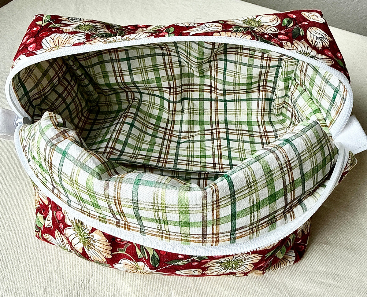 Close-up of the open Berry Blossom quilted boxy bag showing its empty green-and-cream plaid lining and white zipper.