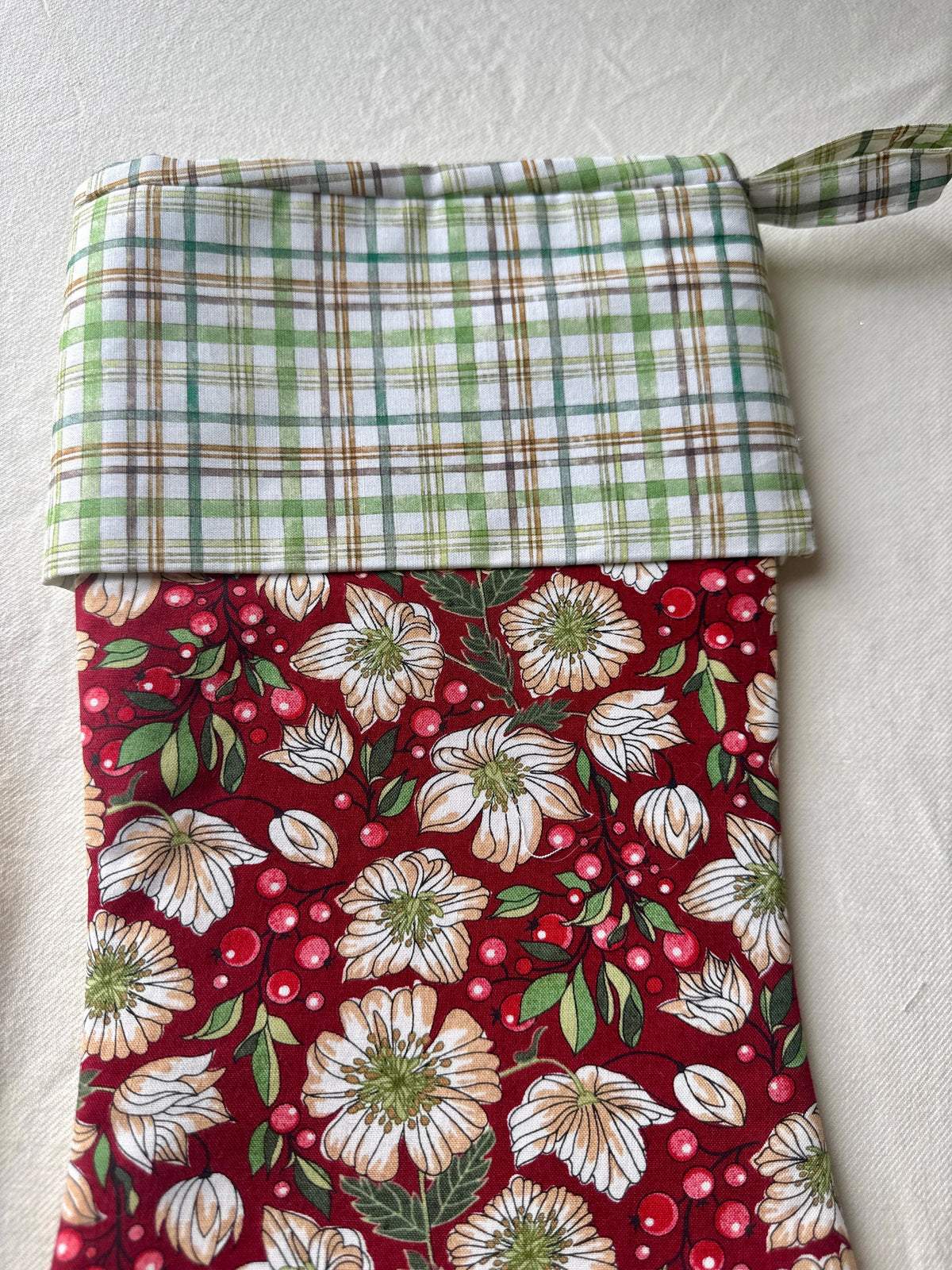 Close-up of the Berry Blossom stocking’s green-and-cream plaid cuff, hanging loop, and burgundy floral fabric.