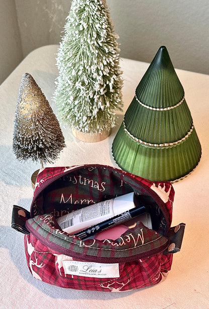 Open with front rolled out, Highland Stag boxy bag filled with cosmetics, showing the holiday-lettering lining and burgundy zipper