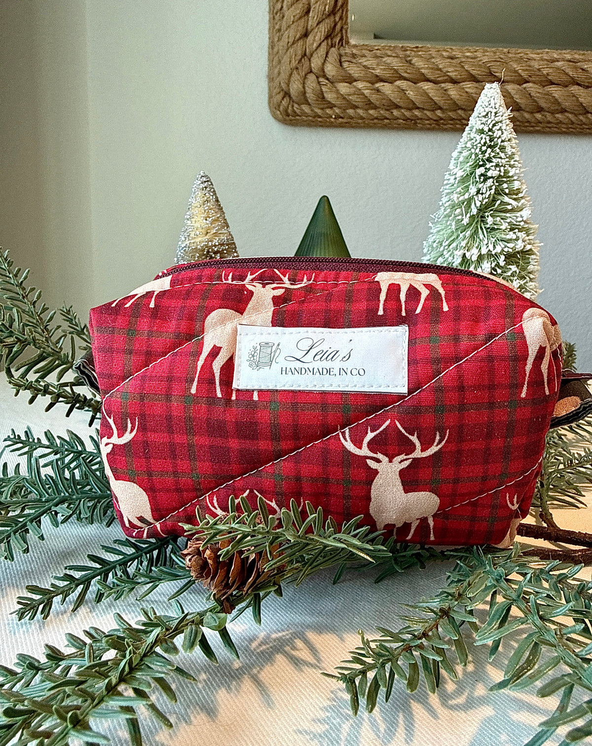Small Highland Stag quilted boxy bag in red plaid with cream stag print and Leia’s handmade label, styled with winter greenery