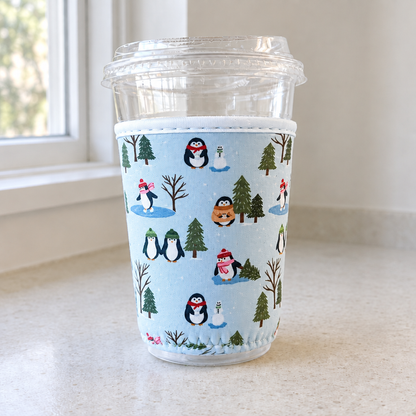 Holiday Penguins cup cozy on a neutral counter by a window